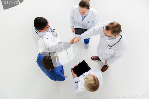 Image of doctors with tablet pc doing handshake at hospital