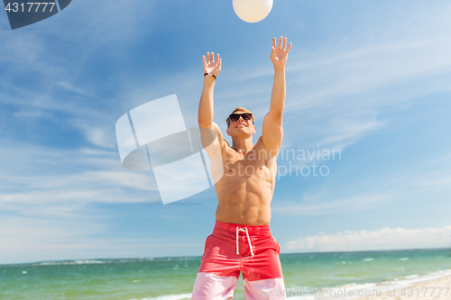 Image of young man with ball playing volleyball on beach