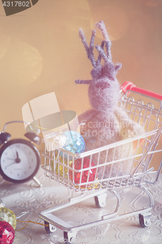 Image of Christmas decorations and elk in shopping trolley, retro toned