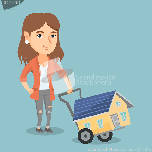 Image of Young caucasian woman with a house on a trolley.