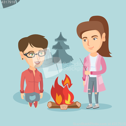 Image of Two friends sitting around bonfire in the camping.