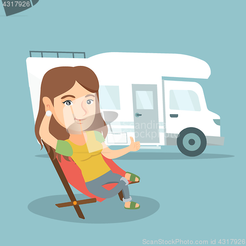 Image of Woman sitting in a chair in front of camper van.