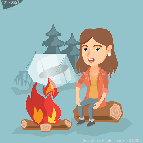 Image of Woman sitting on log near campfire in the camping.