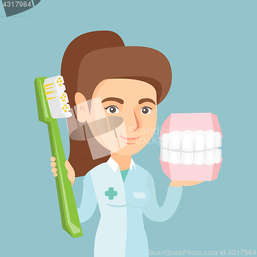 Image of Dentist with a dental jaw model and a toothbrush.