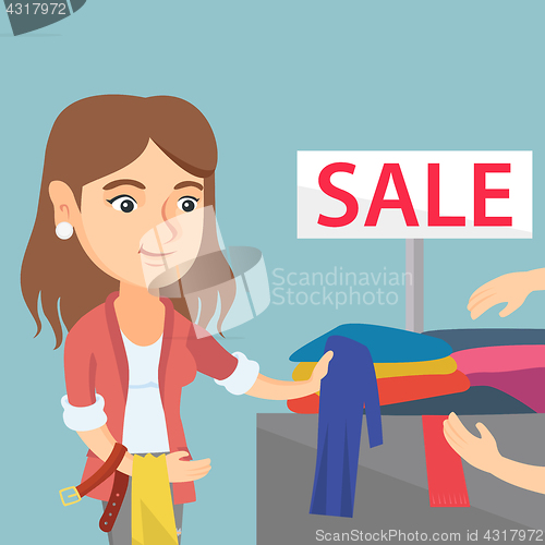 Image of Young woman choosing clothes in the shop on sale.