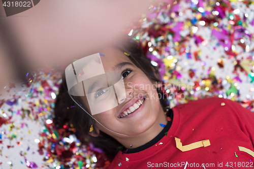 Image of kid blowing confetti while lying on the floor