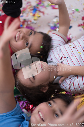 Image of kids  blowing confetti while lying on the floor
