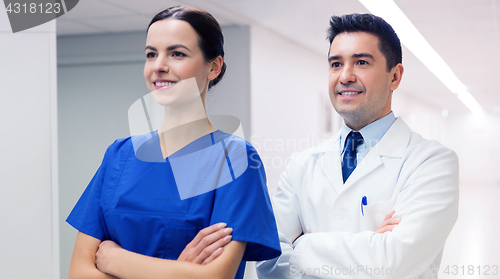 Image of smiling doctor in white coat and nurse at hospital