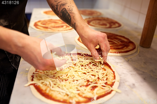 Image of cook adding grated cheese to pizza at pizzeria