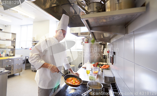 Image of happy male chef cooking food at restaurant kitchen