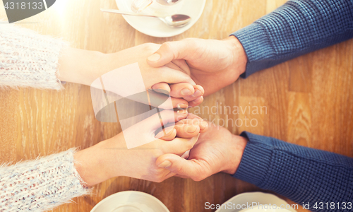 Image of close up of couple holding hands at restaurant
