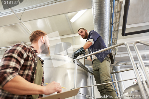 Image of men with clipboard at brewery or beer plant kettle