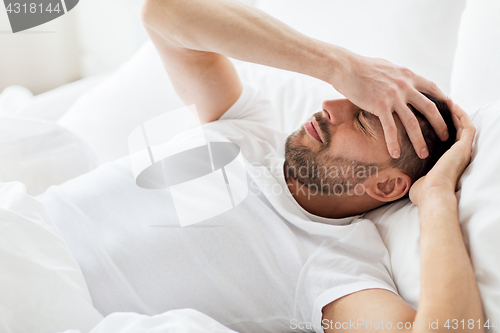 Image of man in bed at home suffering from headache