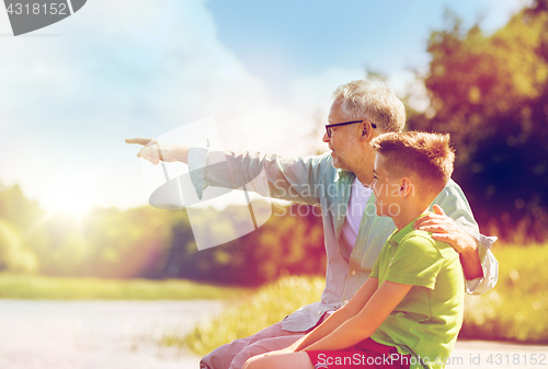 Image of grandfather and grandson sitting on river berth