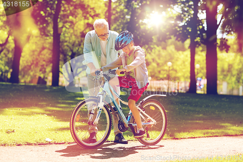 Image of grandfather and boy with bicycle at summer park