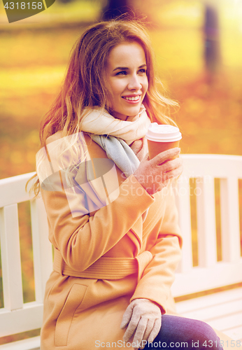 Image of happy young woman drinking coffee in autumn park