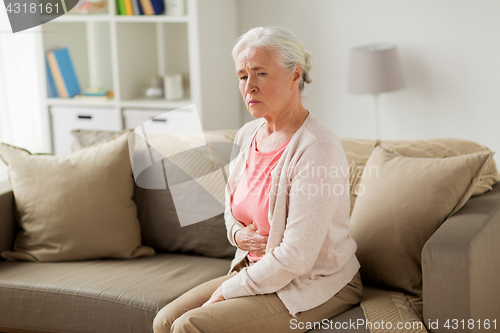 Image of senior woman suffering from stomach ache at home