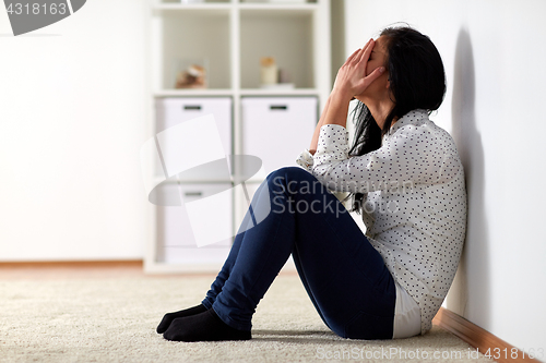 Image of unhappy woman crying on floor at home