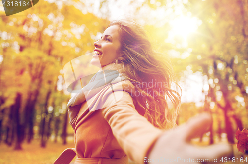 Image of beautiful happy young woman walking in autumn park