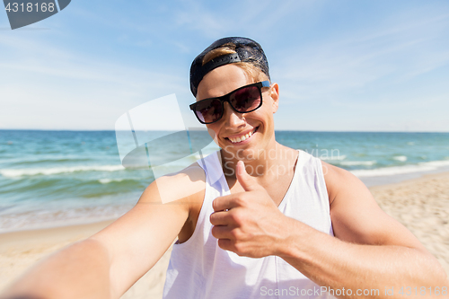 Image of man in sunglasses taking selfie on summer beach
