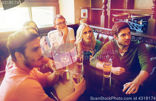 Image of friends with beer watching football at bar or pub