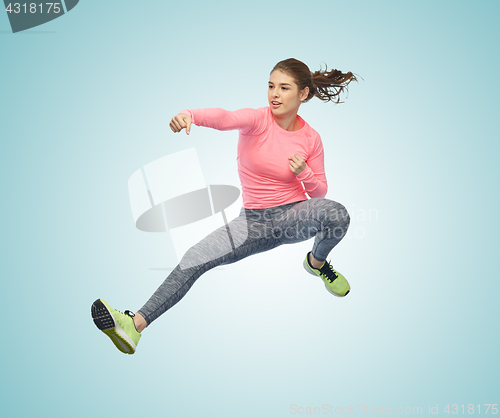 Image of happy sporty young woman jumping in fighting pose