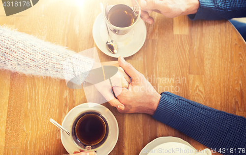 Image of close up of couple holding hands at restaurant