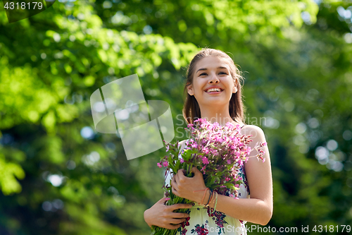 Image of happy young woman with flowers in summer park