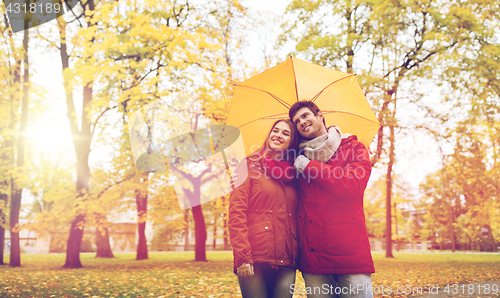 Image of smiling couple with umbrella in autumn park