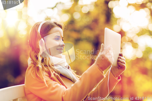 Image of woman with tablet pc and headphones in autumn park