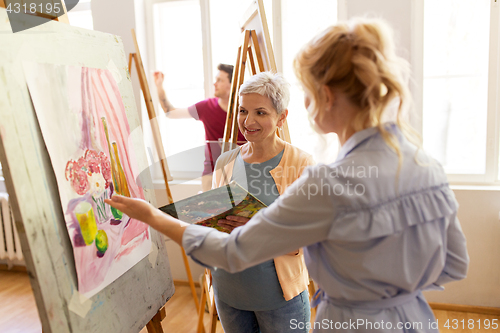 Image of artists discussing painting on easel at art school