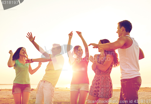 Image of smiling friends dancing on summer beach