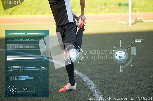 Image of soccer player stretching leg on field football