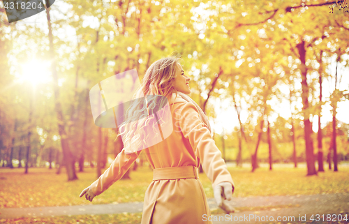 Image of beautiful happy young woman walking in autumn park
