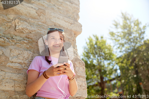 Image of happy young woman with smartphone and earphones