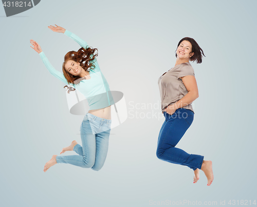 Image of happy different women jumping over blue