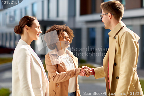 Image of happy people shaking hands on city street