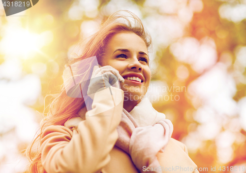 Image of woman calling on smartphone in autumn park