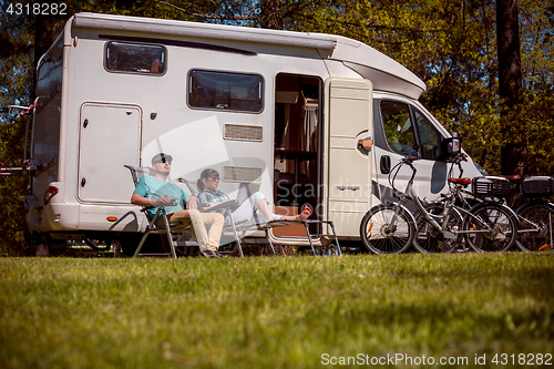 Image of Woman with a man resting near motorhomes in nature. Family vacat