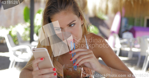 Image of Woman relaxing with phone in resort