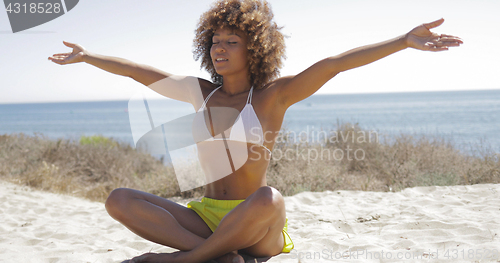 Image of Concentrated woman meditating on beach