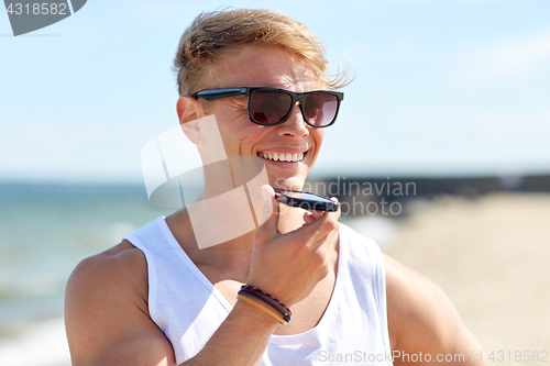 Image of smiling man calling on smartphone on summer beach