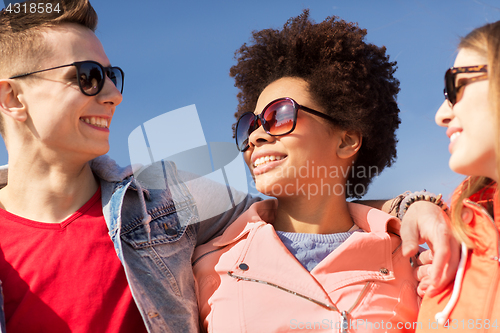 Image of happy teenage friends in shades talking on street