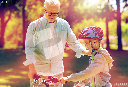 Image of grandfather and boy with bicycle at summer park