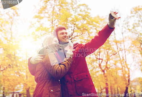 Image of couple taking selfie by smartphone in autumn park