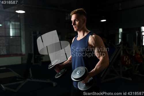 Image of young man with dumbbells exercising in gym