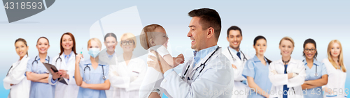 Image of happy doctor or pediatrician with baby over blue