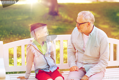 Image of grandfather and grandson talking at summer park