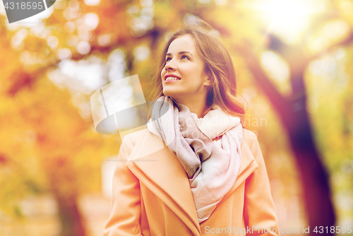 Image of beautiful happy young woman walking in autumn park