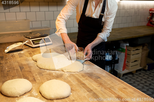 Image of baker portioning dough with bench cutter at bakery